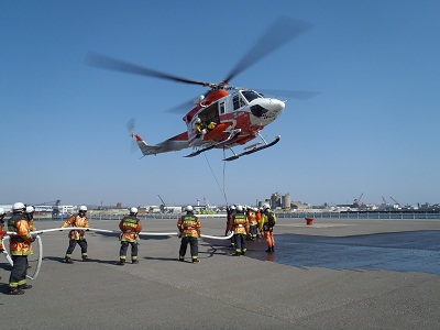 ヘリコプターに取り付けてある、消火バケツに水を入れる写真